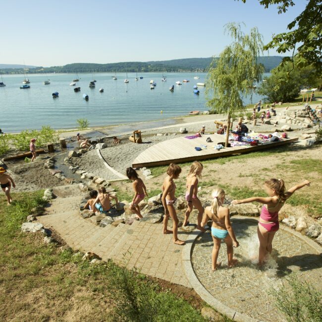Spielende Kinder auf dem Wasserspielplatz am See